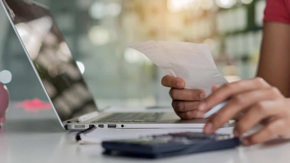 Facturation électronique obligatoire en 2026 : êtes-vous prêts ? personne qui consulte son ordinateur avec des factures à la main